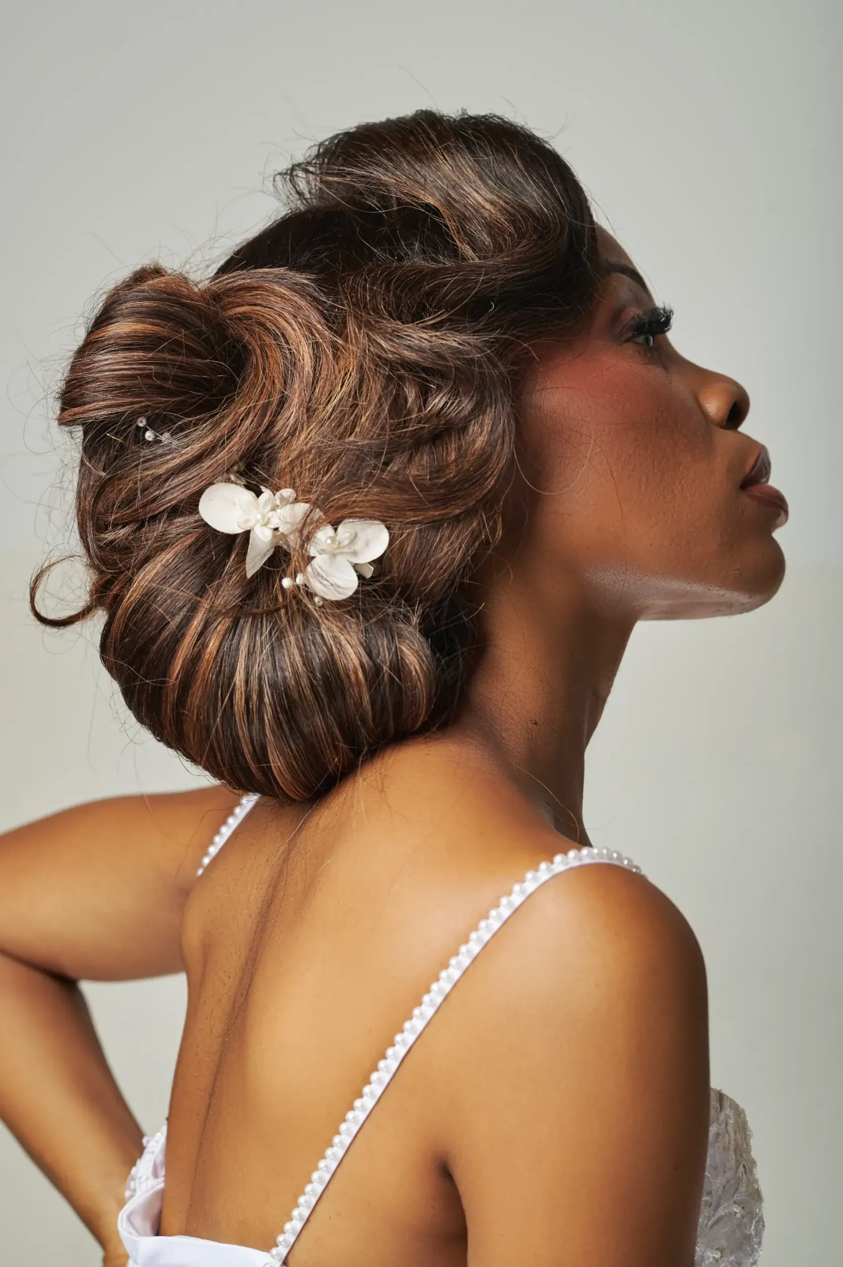Chignon signature orné de fleurs, vu de profil